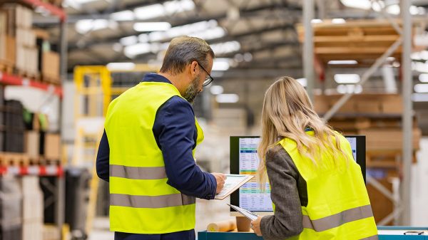 Eine Fachkraft für Logistikdienstleistungen prüft gemeinsam mit einer Kollegin Unterlagen zur Warenbewegung. Die Aufnahme steht für strukturierte Arbeitsabläufe und professionelle Personaldienstleistungen im Lagerumfeld.